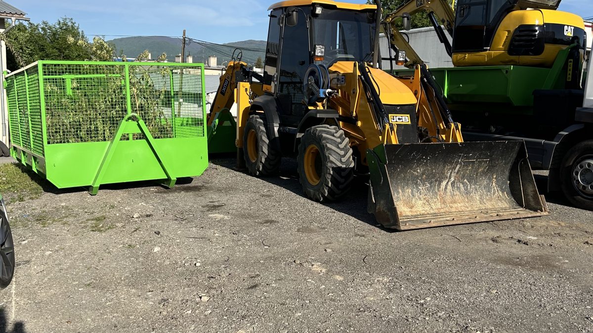 Traktorbager JCB 3CX Compact a bager CAT zaparkované vedľa zeleného kontajnera. Stroje spoločnosti po-bagrujem.sk pripravené na výkopové práce, zemné úpravy a prepravu stavebného materiálu. Ideálne na realizáciu výkopových prác a zemných prác na rôznych typoch stavieb a projektov.