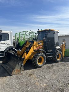 Traktorbager JCB 3CX Compact pripravený na výkopové práce a zemné úpravy, zaparkovaný vedľa nákladného vozidla spoločnosti po-bagrujem.sk. Kompaktný bager ideálny na výkopové a zemné práce, úpravy terénu a manipuláciu s materiálom na staveniskách rôznych veľkostí.