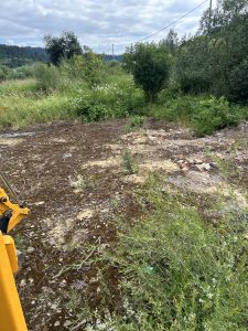 Prírodná plocha so zeleňou a rozbitou pôdou pripravená na zemné a výkopové práce. Pohľad na miesto realizácie úprav terénu, ktoré zabezpečuje spoločnosť po-bagrujem.sk. Lokalita vhodná na prípravu pozemku pre stavebné projekty a ďalšie zemné práce.